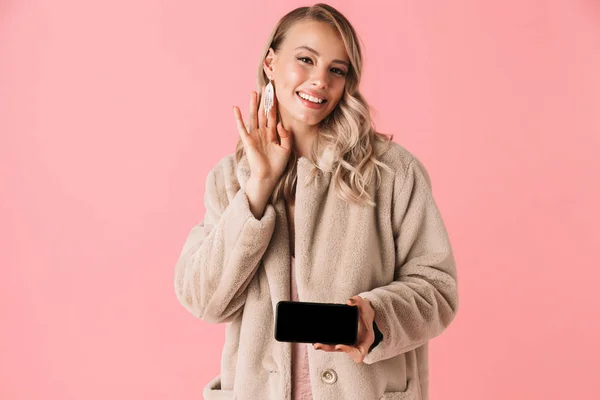 携帯電話のディスプレイのピンクの壁の背景に分離ポーズ美しい幸せな若いきれいな女性. — ストック写真