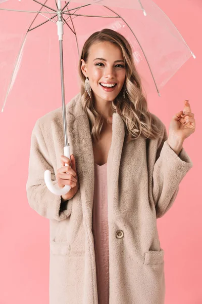 Feliz jovem bonita mulher posando isolado sobre rosa parede fundo segurando guarda-chuva . — Fotografia de Stock