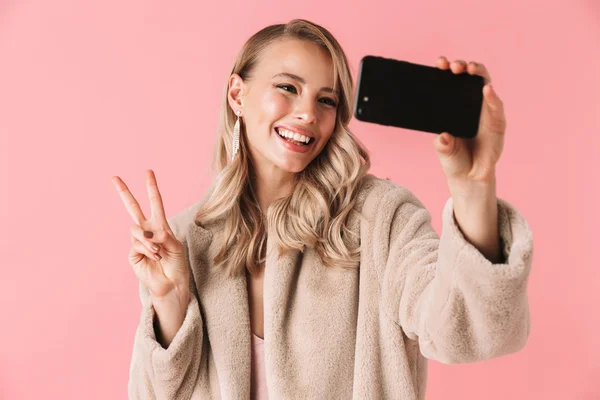 Jonge mooie vrouw poseren geïsoleerde over roze muur achtergrond een selfie nemen per mobiele telefoon. — Stockfoto