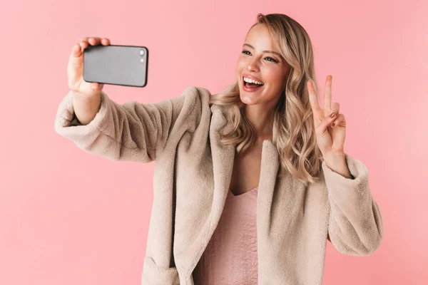 Jonge mooie vrouw poseren geïsoleerde over roze muur achtergrond een selfie nemen per mobiele telefoon. — Stockfoto