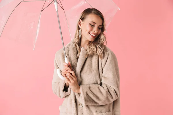 Feliz joven bonita mujer posando aislada sobre fondo de pared rosa sosteniendo paraguas . — Foto de Stock