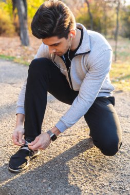 Sporcu kulaklık ile müzik Park açık havada onun bağcıklarımı bağla.