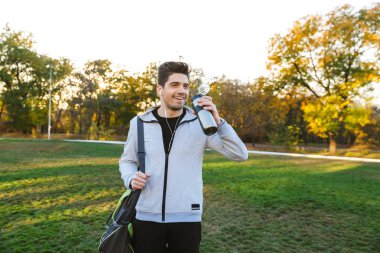 Sporcu açık havada içinde park çanta ile yürüyüş kulaklık ile müzik dinleme.