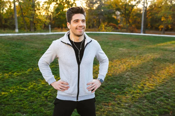 Deportista al aire libre en el parque escuchando música con auriculares tienen un descanso . —  Fotos de Stock