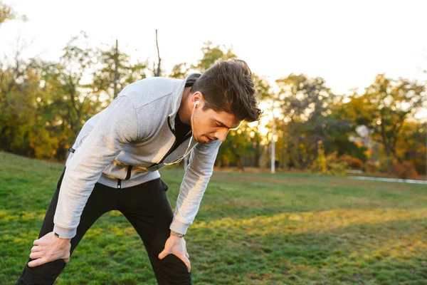 Sporcu açık havada park kulaklık ile müzik dinlemek var bir dinlenme. — Stok fotoğraf