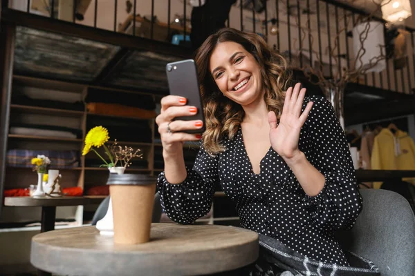 Glimlachend jonge vrouw zitten in het cafe koffie drinken — Stockfoto