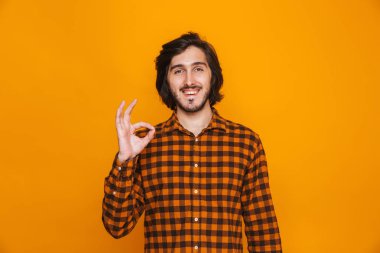 İyi jest gösterilen sarı duvar arka plan üzerinde izole mutlu yakışıklı genç.