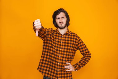 Genç adam başparmak aşağı gösterilen sarı duvar arka plan üzerinde izole sıktı.