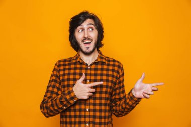 Arka plan sarı duvar işaret içinde izole mutlu yakışıklı genç.