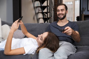 Evde kanepede rahatlatıcı neşeli genç çift
