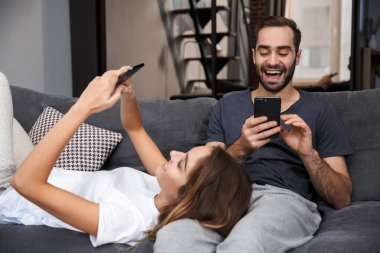 Evde kanepede rahatlatıcı neşeli genç çift