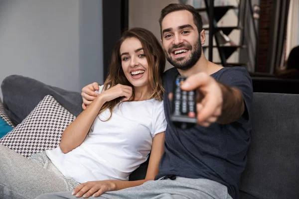 Alegre joven pareja relajándose en sofá en casa — Foto de Stock