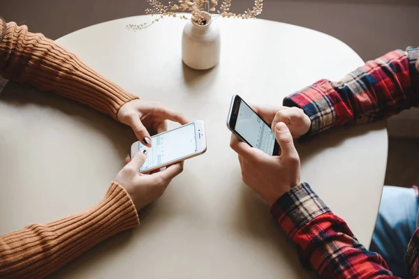 Jonge verliefde paar zitten in Cafe binnenshuis gebruik mobiele telefoon. — Stockfoto