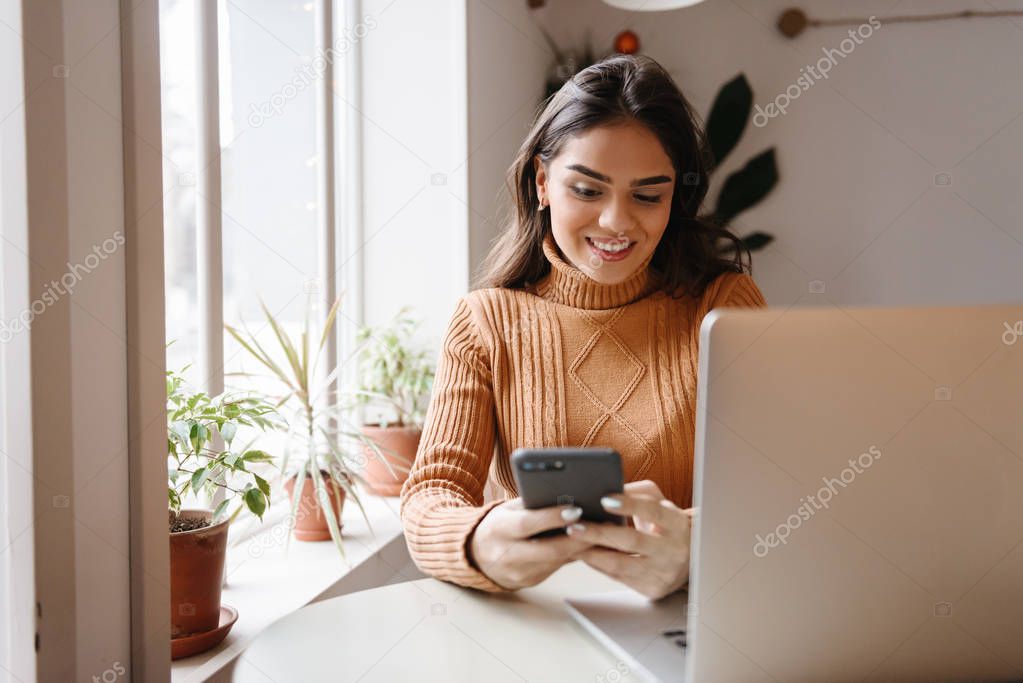Pretty beautiful woman sitting in cafe indoors using laptop computer.