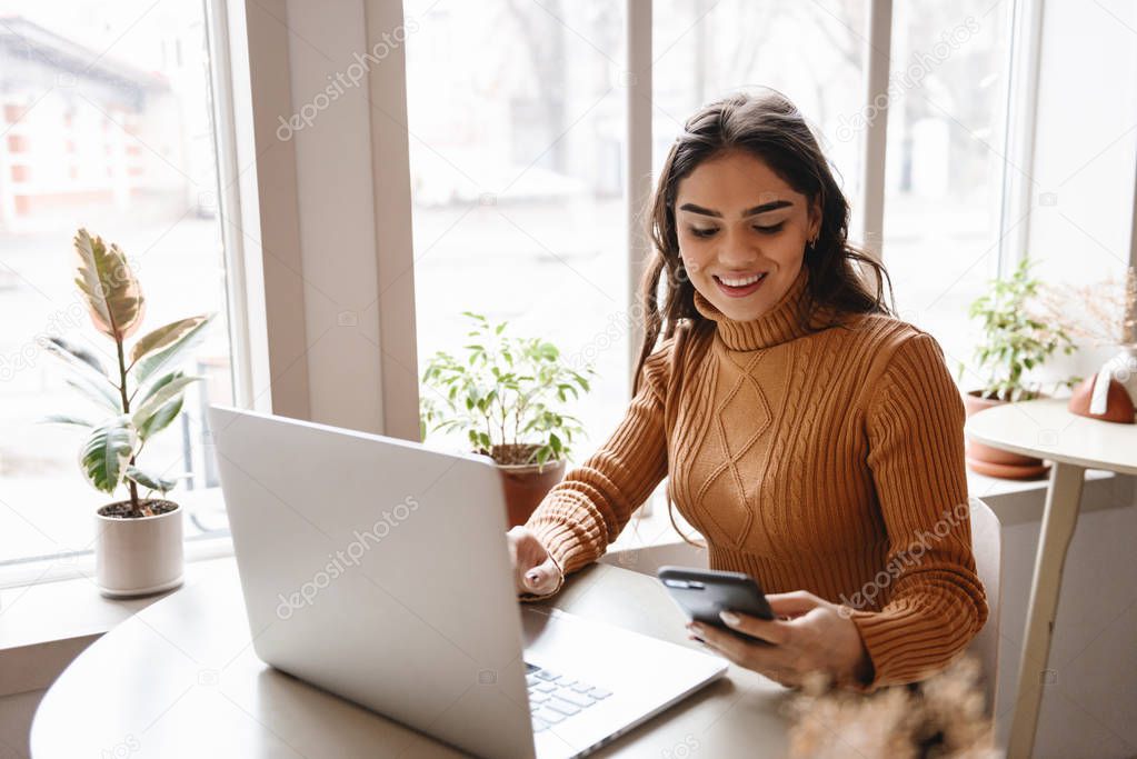 Pretty beautiful woman sitting in cafe indoors using laptop computer.