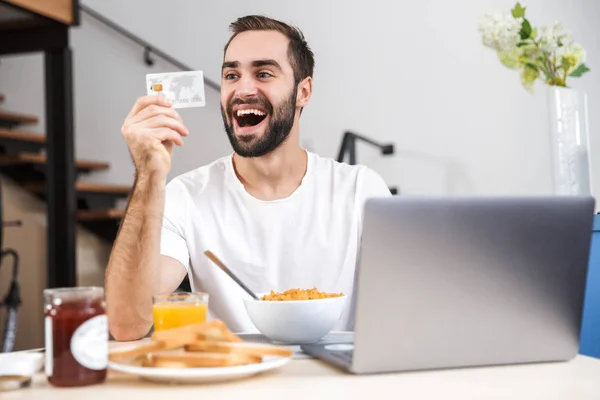 Щасливий молодий чоловік снідає на кухні — стокове фото