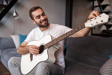 Beyaz adamın otururken akustik gitar çalmak fotoğraf 