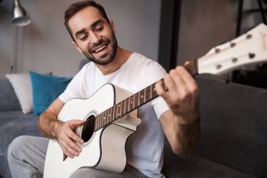 Esmer adam s üzerinde otururken akustik gitar çalmak fotoğrafı