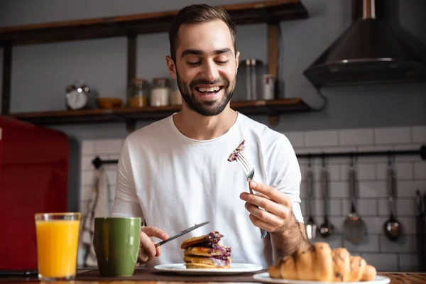 Bilden av brunett kille 30s äta mat medan du äter frukost — Stockfoto