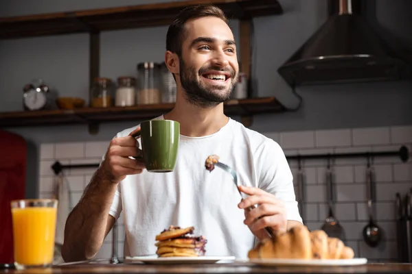 Bild av glada killen 30s äta mat medan du äter frukost i mo — Stockfoto