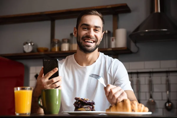 Porträtt av orakad mannen 30s hålla och använda smartphone samtidigt — Stockfoto