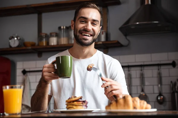 Bilden av snygg kille 30s äta mat medan du äter frukost — Stockfoto