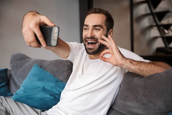 Photo of optimistic bachelor holding and taking selfie on cell p — Stock Photo, Image