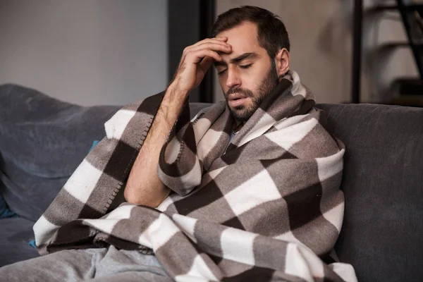 Foto de un hombre infeliz que tiene temperatura y se ve enfermo mientras s —  Fotos de Stock