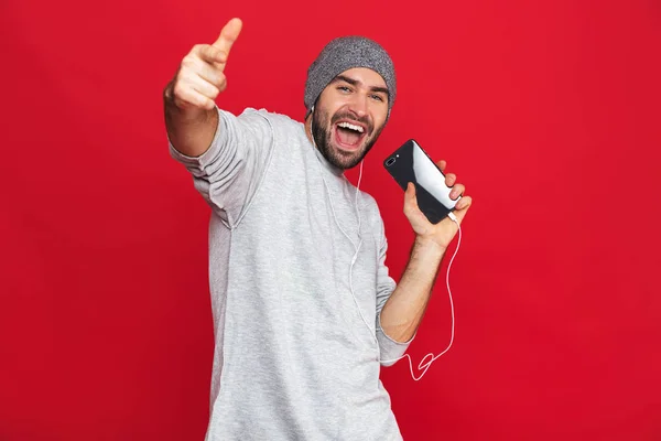 Image d'un homme attrayant des années 30 portant des écouteurs tenant un téléphone portable — Photo