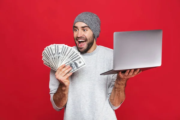 Foto de cara feliz segurando dinheiro em dinheiro e prata laptop isolado — Fotografia de Stock