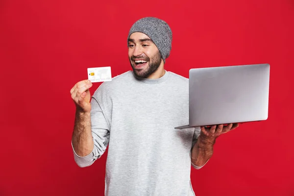 持信用卡和银色笔记本电脑的积极的家伙的照片 — 图库照片