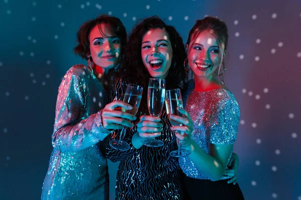 Mulheres felizes posando isolado com luzes de bola de discoteca segurando óculos com champanhe . — Fotografia de Stock