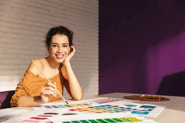 Mulher artística alegre escolhendo a cor da pintura em uma paleta — Fotografia de Stock