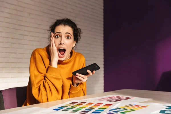 Cheerful artistic woman choosing paint color on a palette