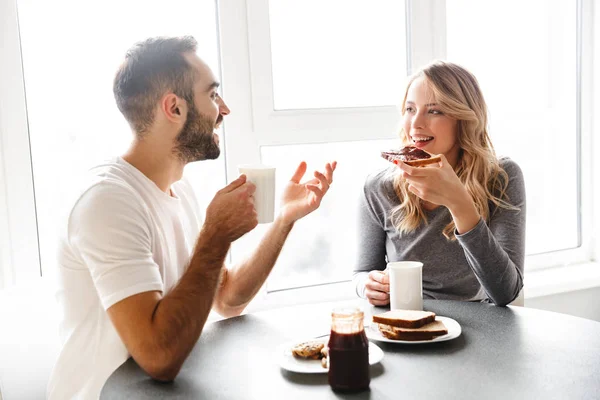Молода любляча пара, сидячи на кухні, сніданок розмовляє один з одним . — стокове фото