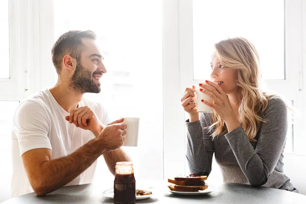 Молода любляча пара, сидячи на кухні, сніданок розмовляє один з одним . — стокове фото
