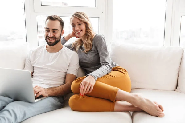 Increíble pareja amorosa sentada en casa usando computadora portátil . —  Fotos de Stock