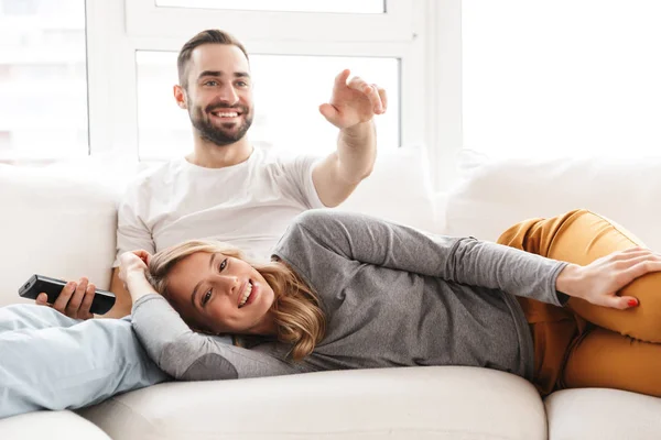 Удивительная любящая пара, сидящая дома, смотрит телевизор с пультом дистанционного управления . — стоковое фото