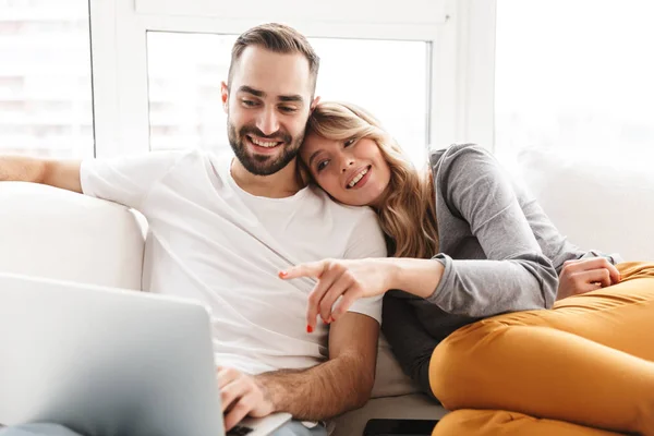 Increíble pareja amorosa sentada en casa usando computadora portátil . — Foto de Stock