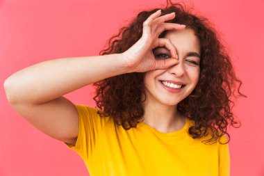 Sevimli güzel genç kıvırcık kız iyi jest gösterilen kırmızı duvar arka plan üzerinde izole poz.