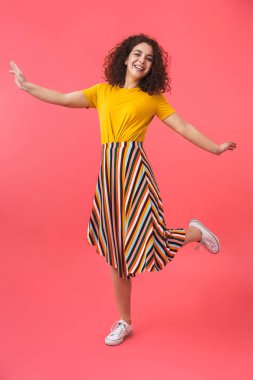 Kırmızı duvar arka plan üzerinde izole poz sevimli mutlu güzel genç kıvırcık kız.