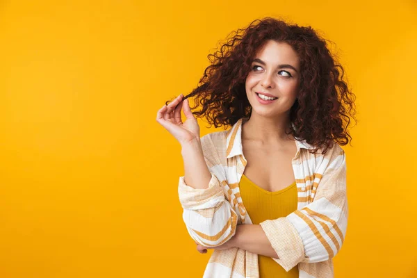 Imagem de mulher adorável 20s tocando seu cabelo encaracolado e olhando — Fotografia de Stock