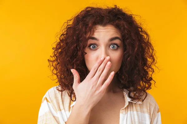 Lockiges Mädchen posiert isoliert über gelbem Wandhintergrund, der den Mund bedeckt. — Stockfoto