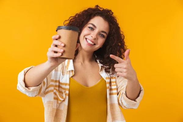 Hermosa chica rizada joven emocional posando aislado sobre fondo amarillo de la pared beber café . —  Fotos de Stock