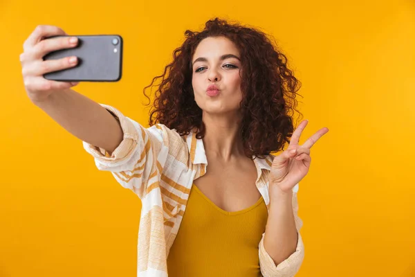 Image of positive woman 20s with curly hair smiling and taking s — Stock Photo, Image