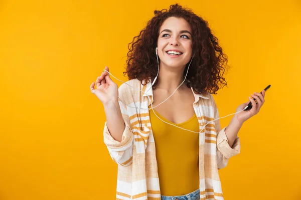 Imagen de mujer complacida de 20 años usando auriculares escuchando música —  Fotos de Stock