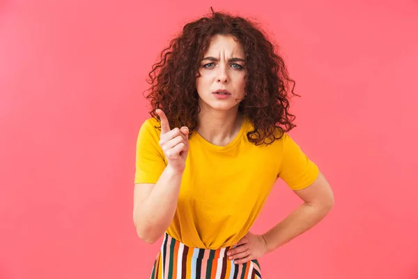 Wütend schöne junge lockige Mädchen posiert isoliert über rote Wand Hintergrund. — Stockfoto