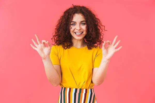 Linda hermosa chica rizada joven posando aislado sobre fondo de pared roja mostrando gesto bien . —  Fotos de Stock