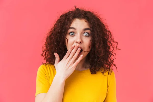 Schockiert verwirrt schöne junge lockige Mädchen posiert isoliert über roter Wand Hintergrund. — Stockfoto