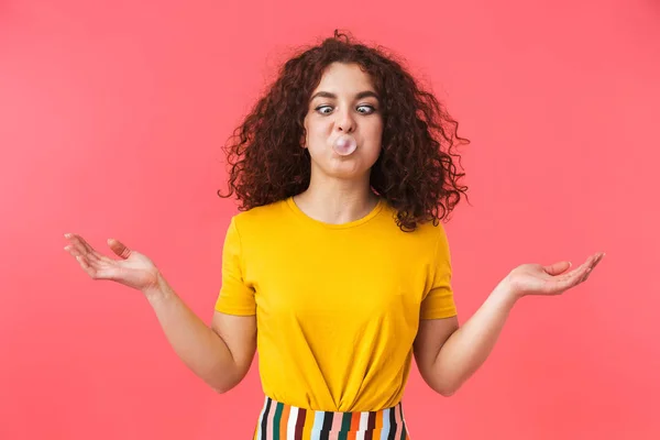 Feliz bela menina encaracolado posando isolado sobre fundo de parede vermelha com chiclete . — Fotografia de Stock